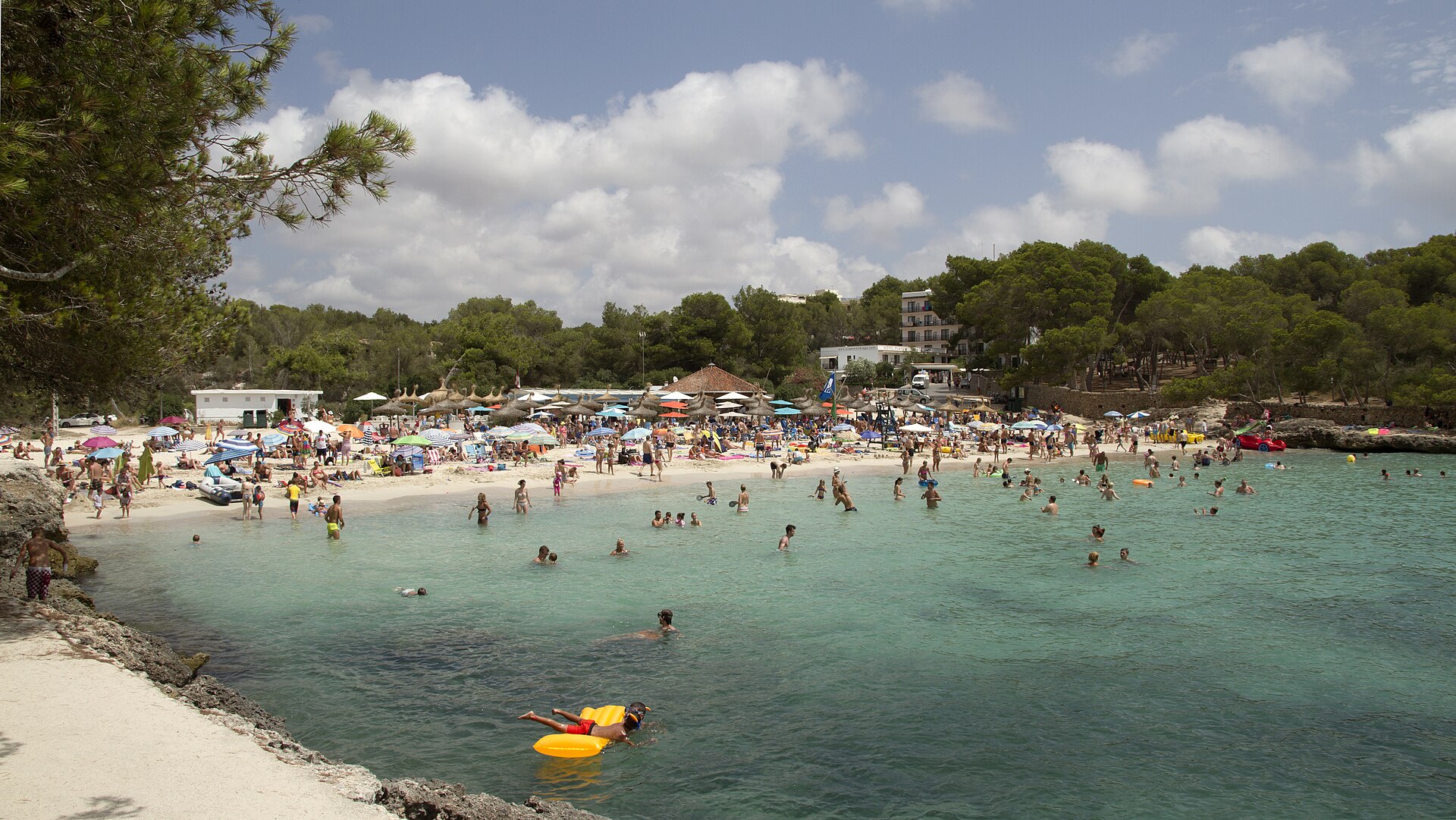 Families on a shallow turquoise beach in the Balearics